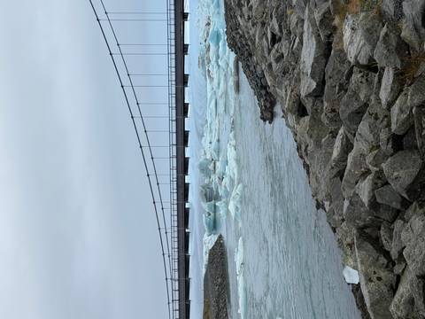 Suspension bridge spanning over glacial icebergs floating in a lagoon.