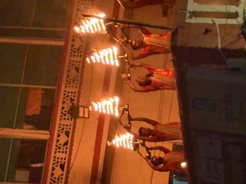 Priests raising multi-tiered oil lamps during an evening Ganga Aarti ceremony.