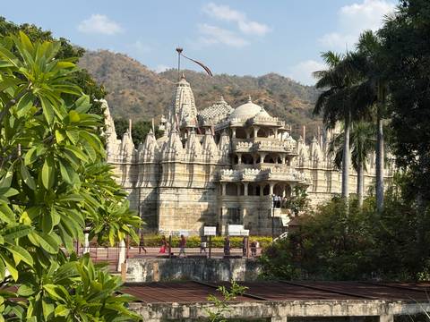 Intricately carved marble Ranakpur Jain temple set against forested hills.