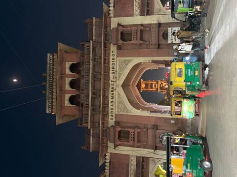 Night scene of Sardar Market gate in Jodhpur with bustling tuk-tuks under moonlight.