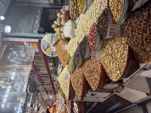 Colorful market stall piled high with nuts, dried fruits and spices labeled with prices.