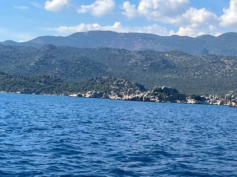 Blue Mediterranean waters with rugged coastal hills in the background.