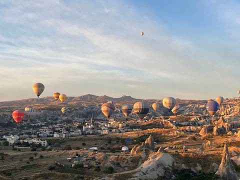 Colorful hot-air balloons fill the early morning sky over Cappadocia’s town and valleys.