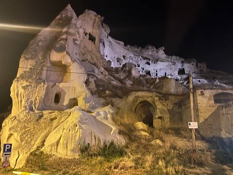Rock-cut cave dwellings illuminated at night in a rugged cliffside setting.