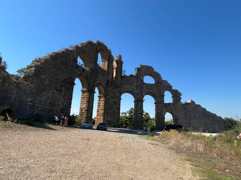Large stone arches of a Roman aqueduct standing under a bright blue sky.