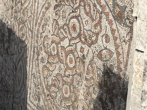 Close-up of an ancient mosaic floor with intricate red and white geometric patterns.