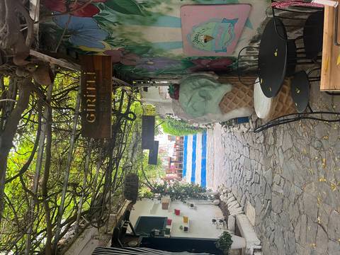 Charming cobblestone alley with grape-covered pergola, colourful signs and an oversized ice-cream sculpture.