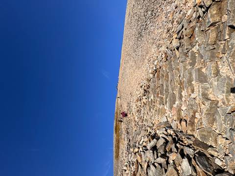 Stone steps ascend a steep, barren mountain slope beneath a vivid blue sky.