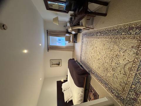 Spacious hotel bedroom featuring a king-size bed, armchairs and large patterned rugs.