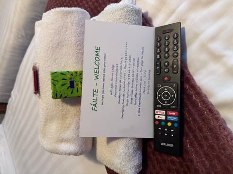 Welcome card, TV remote and towel arranged on a hotel bed.