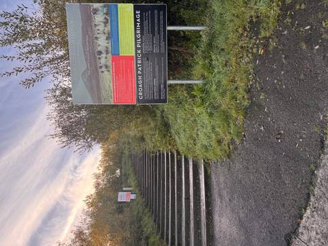 Steps leading into wooded hillside beside Croagh Patrick pilgrimage information boards at dawn light.