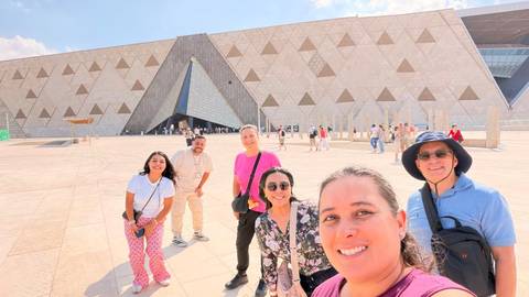 Smiling travelers take a selfie outside the geometric façade of Egypt’s Grand Museum.