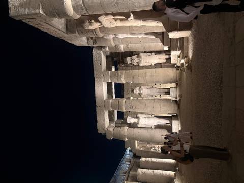 Nighttime lighting accentuates massive statues and columns in Luxor Temple’s courtyard.