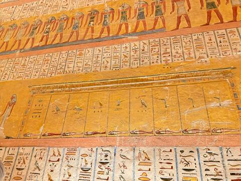 Detailed golden wall friezes and hieroglyphs adorn an ancient Egyptian burial chamber.
