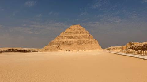 The Step Pyramid of Djoser rises from the desert sands beneath a hazy sky at Saqqara.