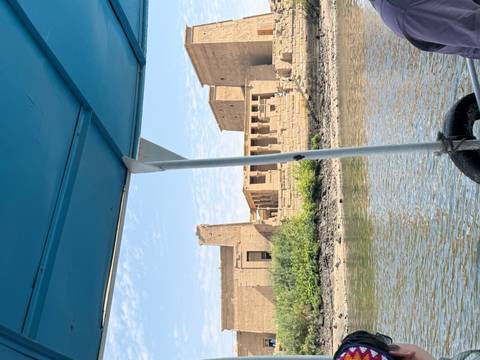 View from a small boat of Philae Temple’s stone colonnades along the Nile island shore.
