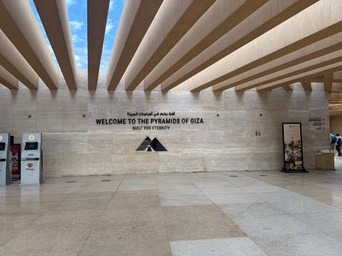 Modern visitor centre wall welcomes guests to the Pyramids of Giza in English and Arabic.