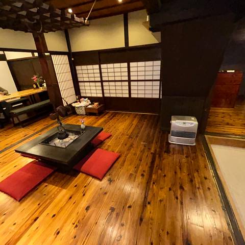Traditional Japanese ryokan room with low hearth table, red cushions and polished wooden floor.