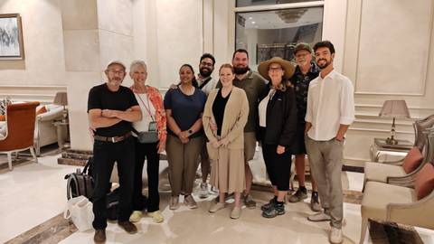 Tour group gathers for a photo in an elegant hotel lobby with marble walls.