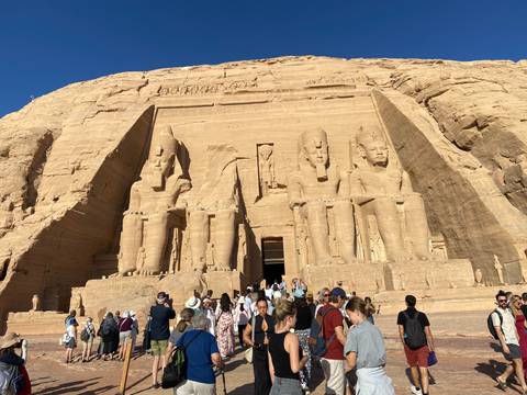 Crowds gather at the colossal façade of Abu Simbel carved into sandstone cliffs.