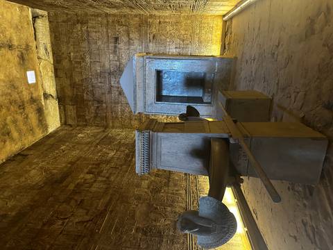 Dimly lit sanctuary inside an ancient Egyptian temple with granite shrine and ceremonial barque.