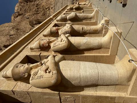 Row of colossal Osiride statues at Hatshepsut’s temple carved from pale sandstone.