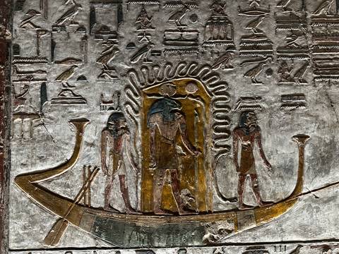 Intricate silver and gold relief of a solar barque with Egyptian gods surrounded by hieroglyphs.