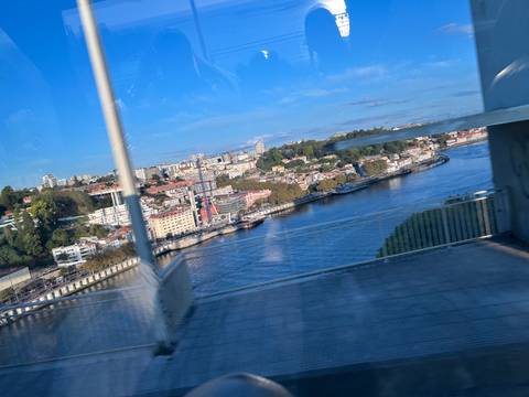 Tilted, slightly blurry river view of a coastal city captured through a bus window and railing