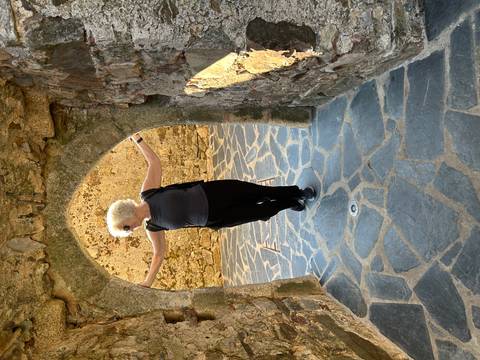 Woman posing playfully under a small stone archway inside a medieval castle ruin