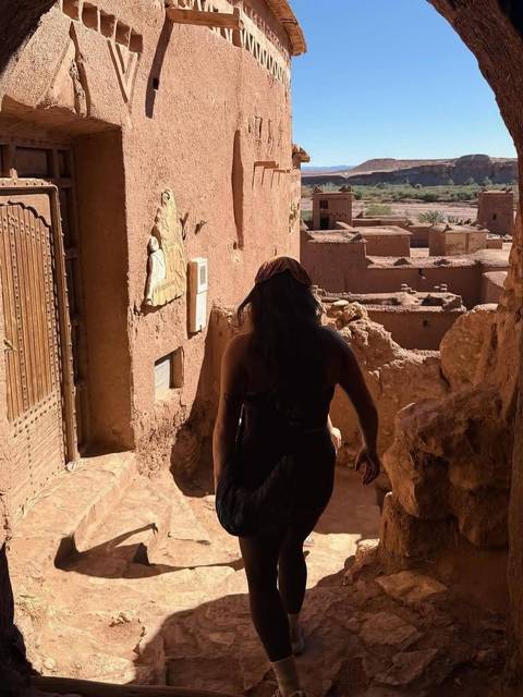 Traveller walking through a narrow earthen passageway in an ancient kasbah