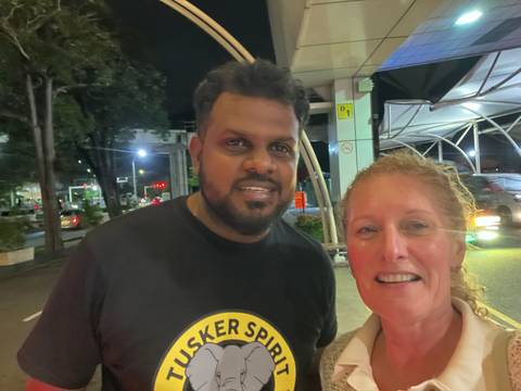 Night-time selfie of two smiling travellers outside a brightly lit transport terminal.