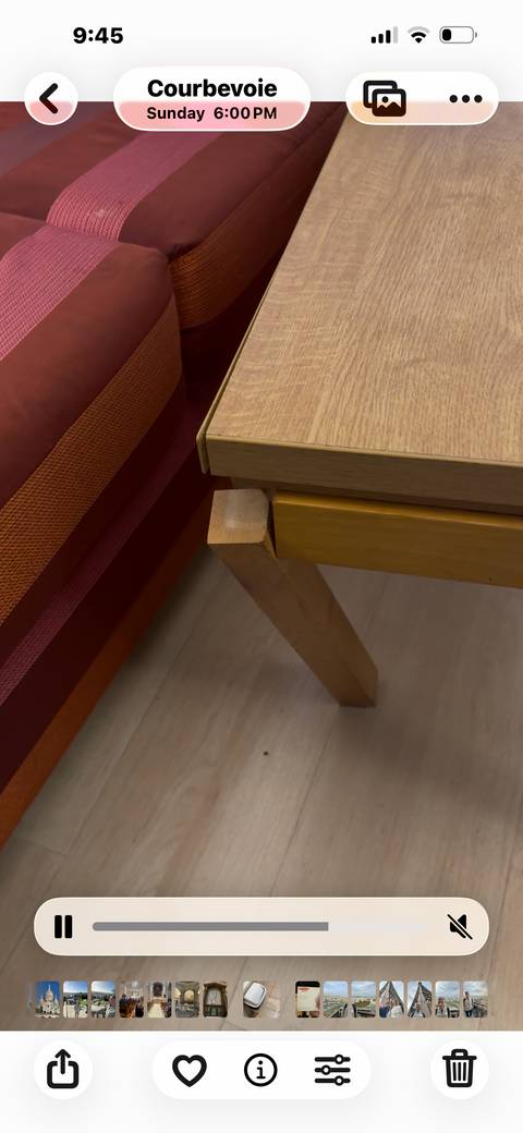 Close-up of a wooden table leg next to a red cushion seat.