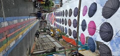 People smiling in a street decorated with umbrellas.