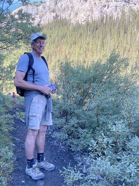 A person hiking through a forest path with a scenic mountain view.