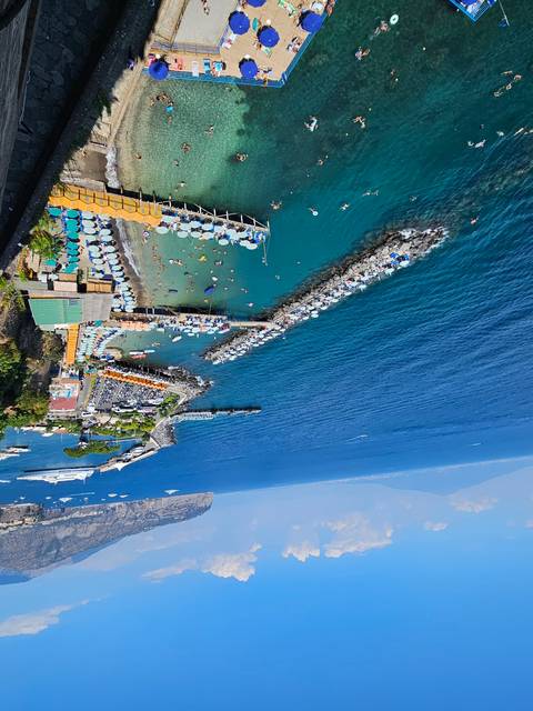 Aerial view of a beach with people swimming and sunbathing.