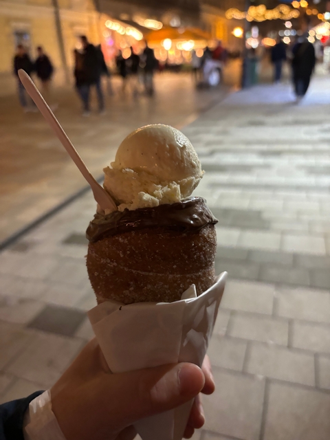 Close-up of a chimney cone filled with ice cream against a tiled ground.