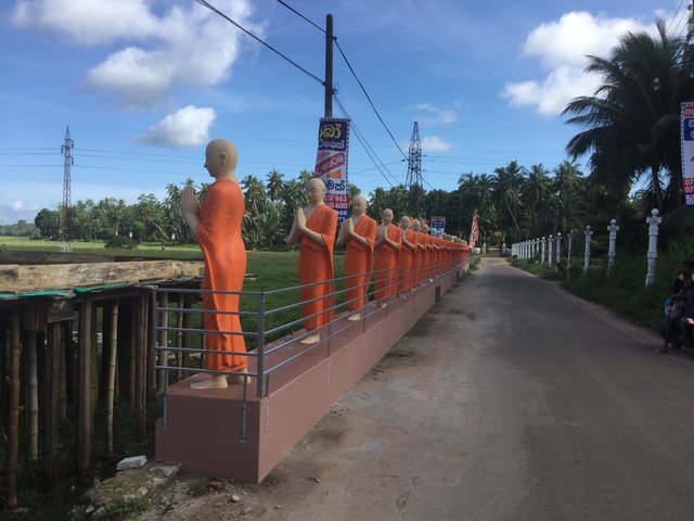 Row of statue figures in a rural setting.