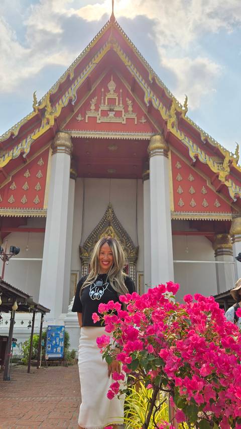 A temple with intricate carvings and pink flowers in the foreground.