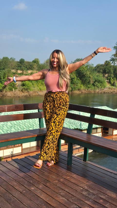 A woman posing on a wooden deck by a river.