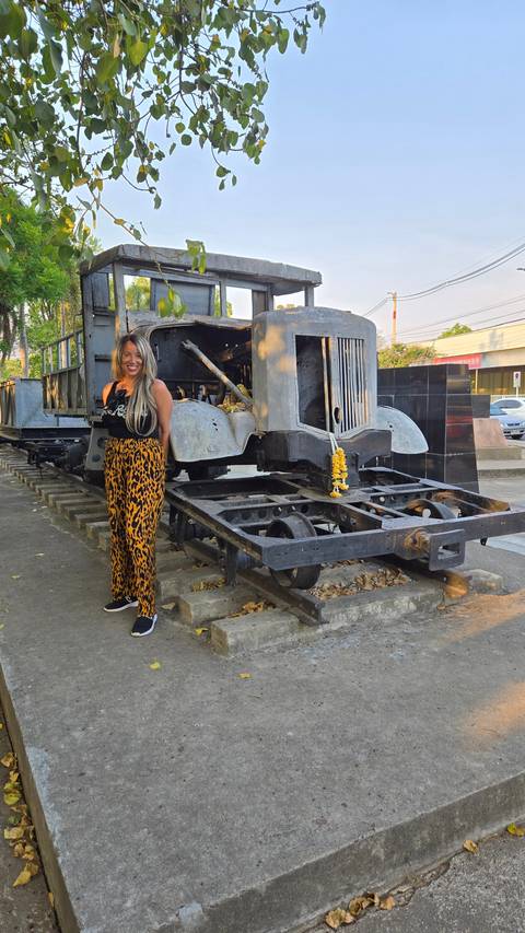 A woman posing with a historical train engine monument.