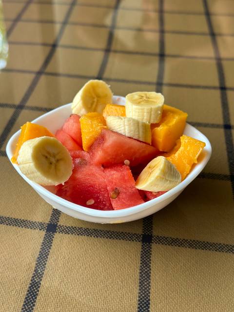 A bowl of cut tropical fruits including watermelon, banana, and mango.