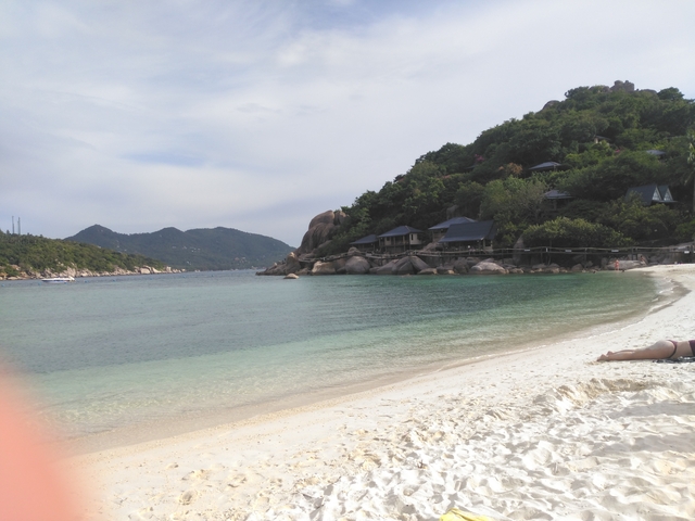 Sandy beach with turquoise water and background hills.