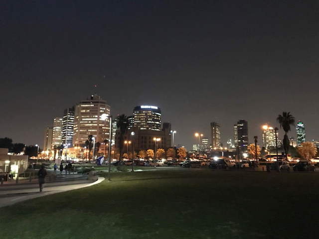 Nighttime skyline of Tel Aviv with illuminated high-rise buildings.