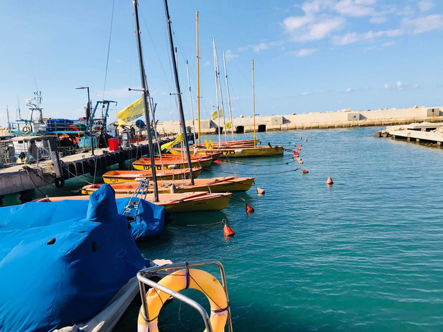 Bright orange dinghies lined up along a stone pier in a small marina.