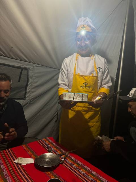 Chef in a tent holding a tray with a headlamp.