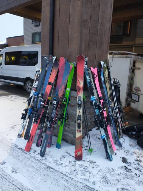 Skis lined up outside on a snowy surface.