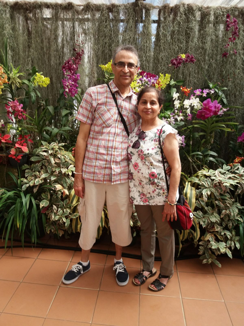 Couple posing in front of flower arrangement.