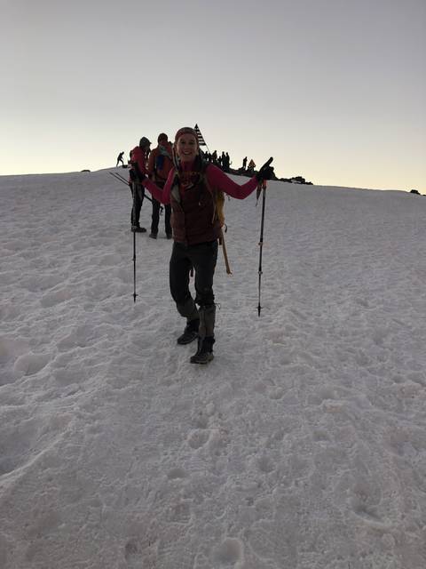 Hiker on a snowy mountain with a group in the background.