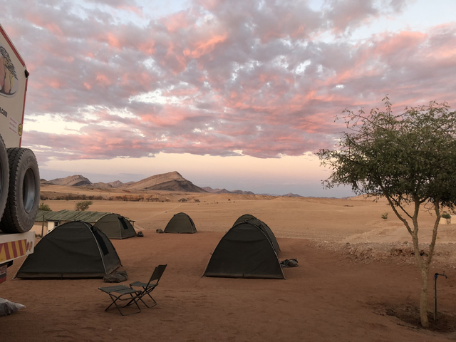 Tents set up in a desert with mountains in the distance.