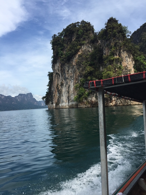 Boat approaching limestone cliffs on a lake.